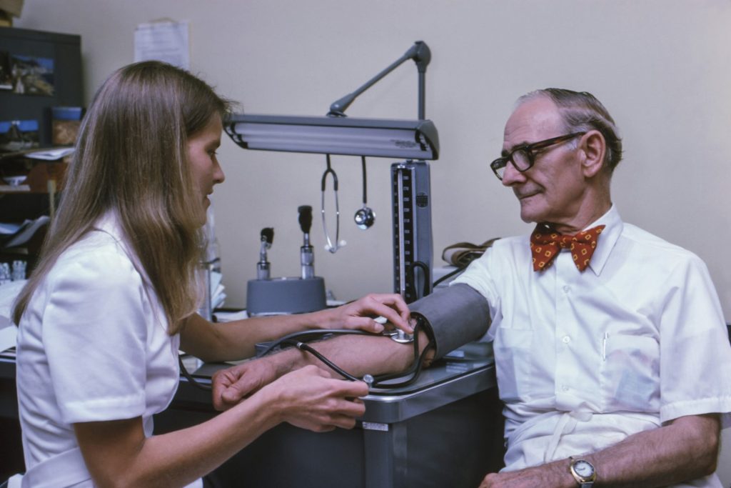 Ein Arzt untersucht den Knöchel eines Patienten mit einem Stethoskop